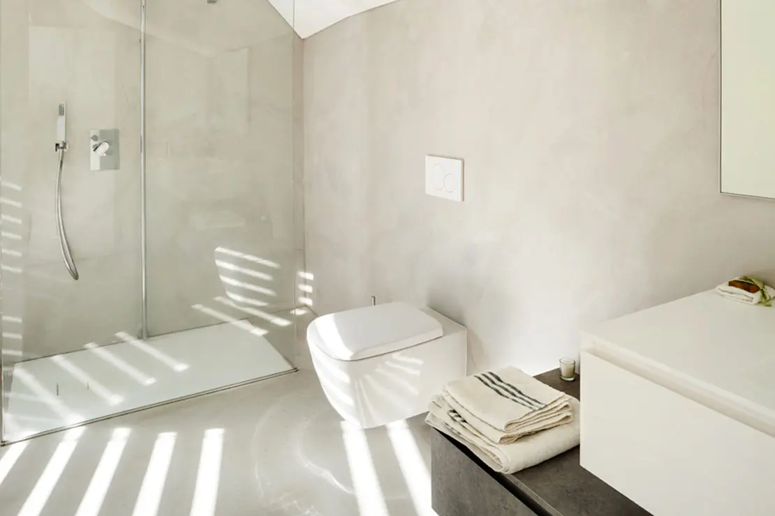 Baño con suelo y paredes de microcemento en matiz luminoso